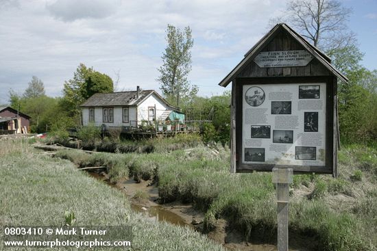 Finn Slough homes at low tide w/ interpretive sign fgnd